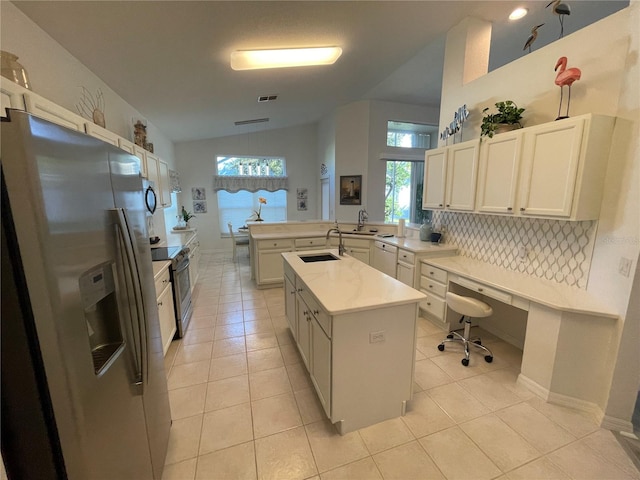 kitchen featuring lofted ceiling, light tile patterned floors, sink, a kitchen island with sink, and stainless steel appliances