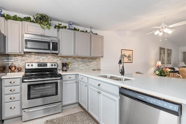 kitchen with ceiling fan, sink, tasteful backsplash, appliances with stainless steel finishes, and vaulted ceiling