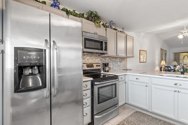 kitchen with ceiling fan, lofted ceiling, sink, stainless steel appliances, and light hardwood / wood-style floors