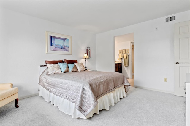 bedroom with ensuite bath and light carpet