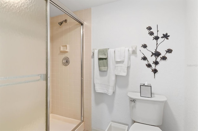 bathroom featuring toilet and a shower with shower door