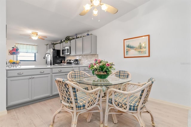 kitchen with ceiling fan, light hardwood / wood-style flooring, stainless steel appliances, and gray cabinetry