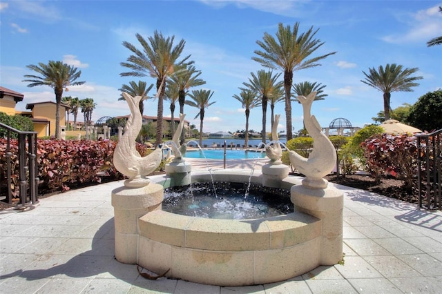 view of patio / terrace with pool water feature, a swimming pool with hot tub, and a water view