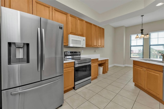 kitchen featuring sink, hanging light fixtures, light tile patterned floors, appliances with stainless steel finishes, and a chandelier