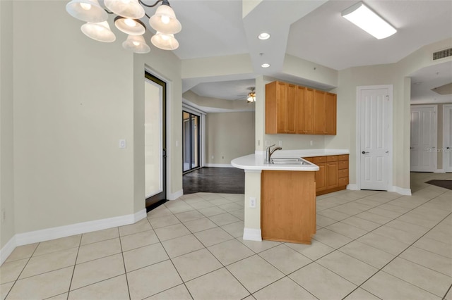 kitchen featuring sink, kitchen peninsula, pendant lighting, light tile patterned floors, and ceiling fan with notable chandelier