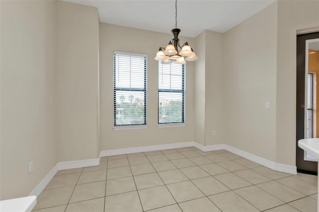 empty room with light tile patterned floors and a chandelier