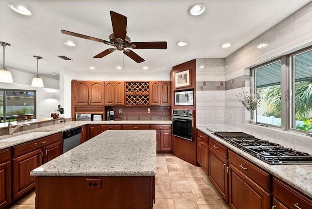 kitchen with gas stovetop, white microwave, stainless steel dishwasher, black oven, and a kitchen island