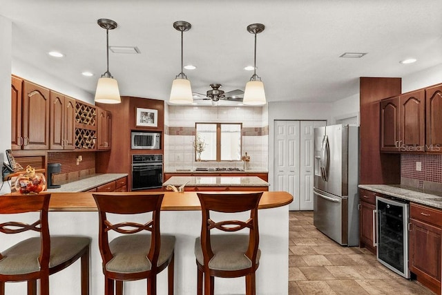 kitchen with decorative backsplash, appliances with stainless steel finishes, beverage cooler, ceiling fan, and hanging light fixtures