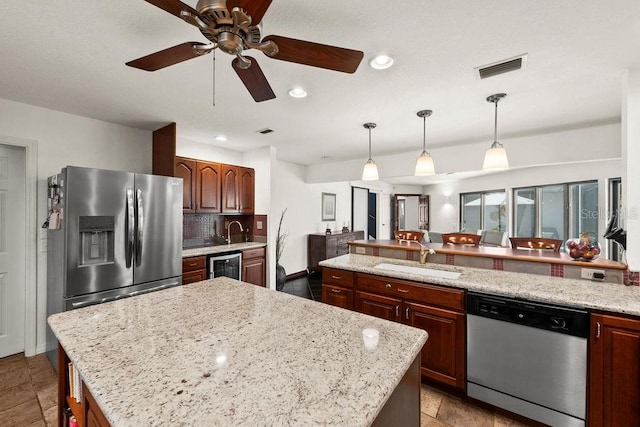 kitchen featuring hanging light fixtures, sink, decorative backsplash, appliances with stainless steel finishes, and a kitchen island