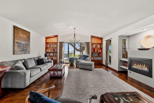 living room with a textured ceiling, built in shelves, vaulted ceiling, and a notable chandelier