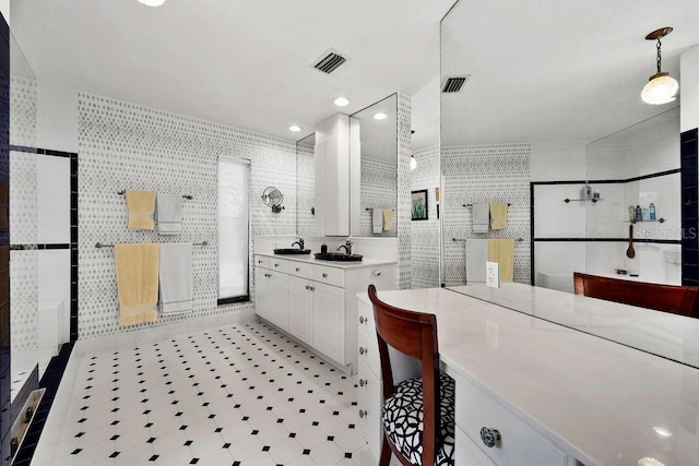 bathroom with tiled shower, vanity, and tile walls