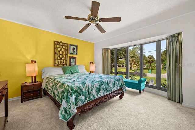 bedroom featuring ceiling fan, light colored carpet, a textured ceiling, and multiple windows