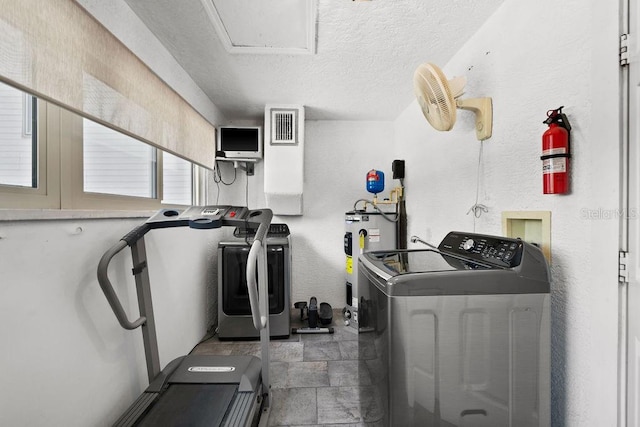 laundry area featuring a textured ceiling, separate washer and dryer, and electric water heater