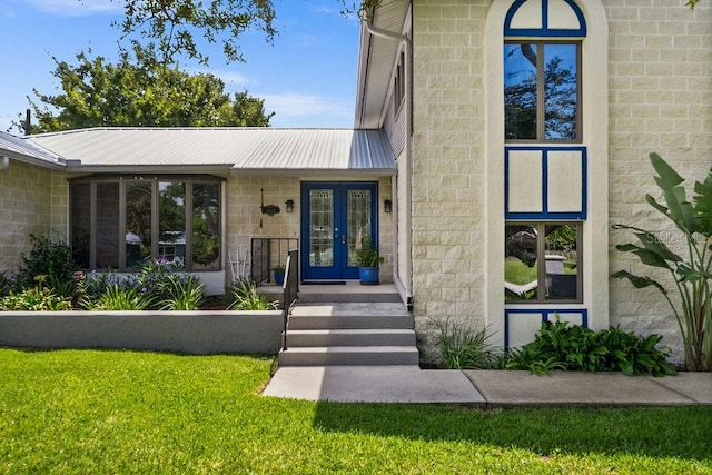 doorway to property featuring french doors and a lawn