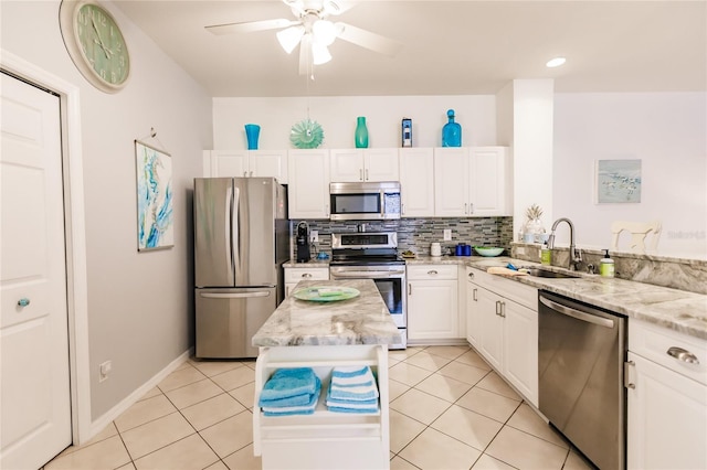 kitchen with ceiling fan, white cabinetry, stainless steel appliances, a center island, and light stone countertops