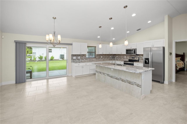 kitchen with light stone counters, decorative light fixtures, a center island with sink, white cabinetry, and stainless steel appliances