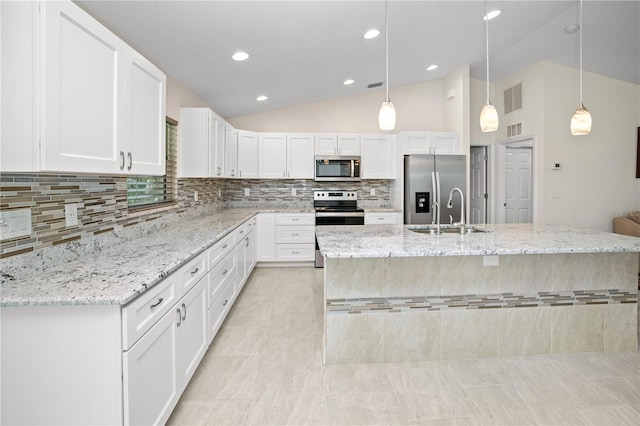 kitchen with hanging light fixtures, white cabinets, stainless steel appliances, lofted ceiling, and sink