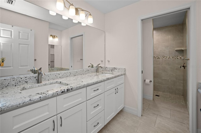 bathroom with tiled shower, vanity, and tile patterned floors