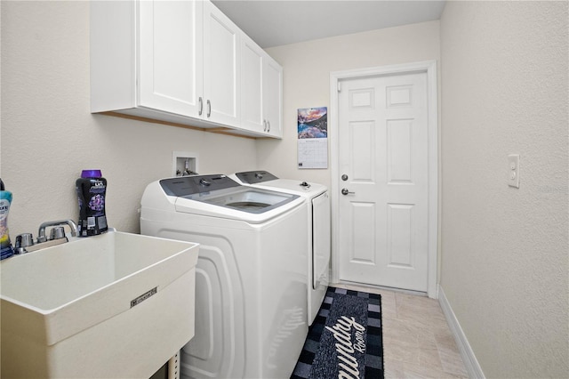 clothes washing area featuring light tile patterned flooring, sink, independent washer and dryer, and cabinets