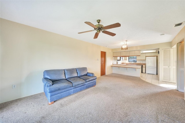 carpeted living room featuring ceiling fan with notable chandelier