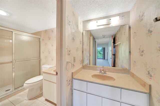 bathroom featuring vanity, a textured ceiling, a shower with door, toilet, and tile patterned floors