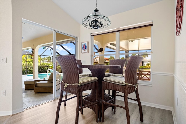 dining area with light hardwood / wood-style flooring, a healthy amount of sunlight, and a notable chandelier