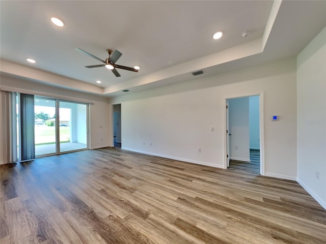 unfurnished room with light hardwood / wood-style flooring, a raised ceiling, and ceiling fan