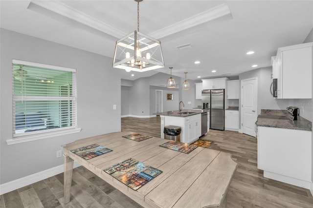 kitchen with an island with sink, decorative light fixtures, sink, and white cabinetry