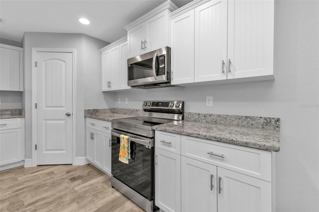 kitchen featuring white cabinetry, light stone countertops, light hardwood / wood-style flooring, and stainless steel appliances