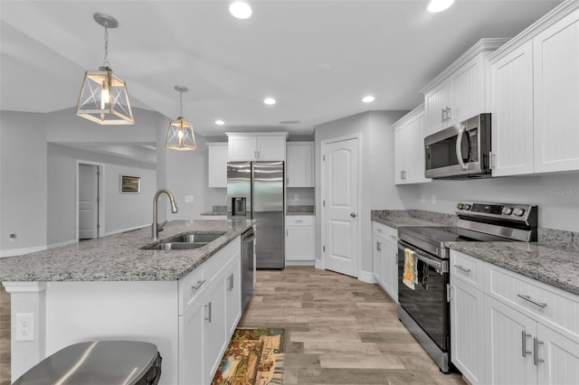 kitchen featuring appliances with stainless steel finishes, hanging light fixtures, white cabinetry, and sink