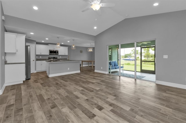 interior space with white cabinetry, pendant lighting, ceiling fan, light hardwood / wood-style flooring, and a center island with sink