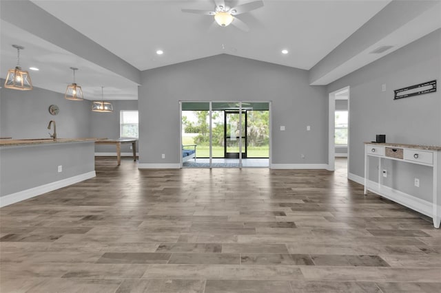 unfurnished living room with lofted ceiling, ceiling fan, a healthy amount of sunlight, and sink