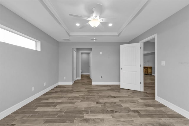 spare room with ceiling fan, a raised ceiling, crown molding, and light hardwood / wood-style flooring