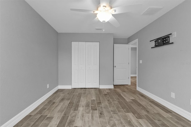 unfurnished bedroom with light hardwood / wood-style floors, ceiling fan, and a closet