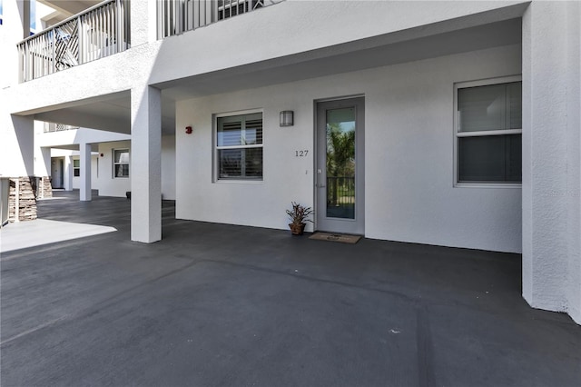 view of exterior entry with a balcony and a patio