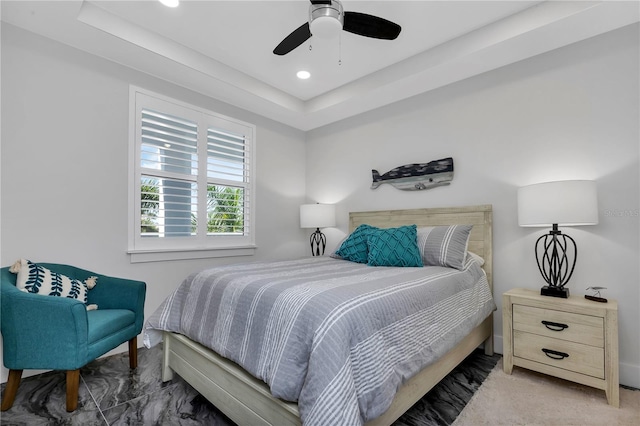 bedroom featuring carpet, ceiling fan, and a raised ceiling