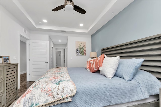 bedroom featuring ceiling fan, a raised ceiling, and dark hardwood / wood-style flooring