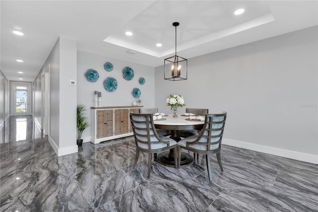 dining area with a notable chandelier and a tray ceiling