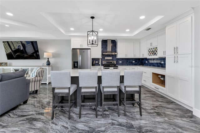 kitchen with wall chimney exhaust hood, a kitchen island with sink, stainless steel appliances, and white cabinets