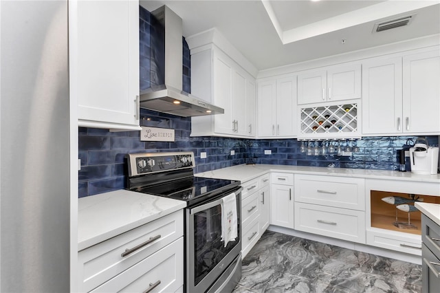 kitchen with backsplash, wall chimney range hood, electric range, and white cabinets