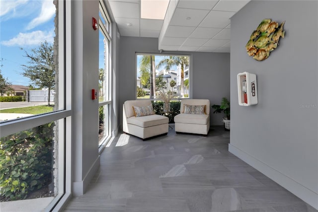 unfurnished sunroom featuring a drop ceiling and a healthy amount of sunlight