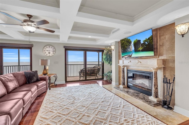 living room with a wealth of natural light, ceiling fan, coffered ceiling, and a fireplace