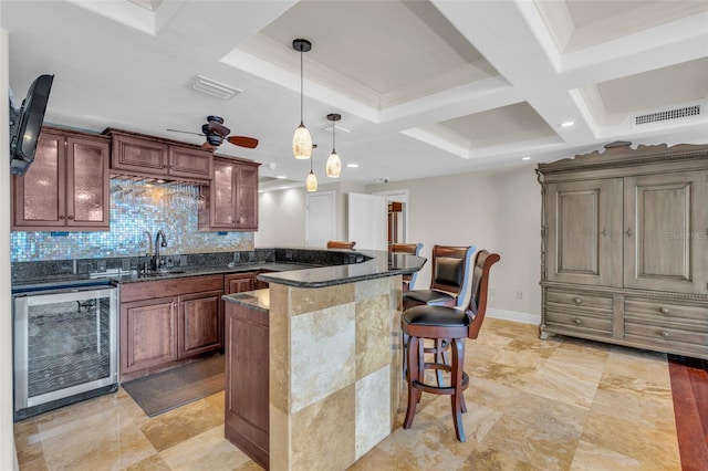 kitchen featuring backsplash, pendant lighting, a center island, beverage cooler, and ceiling fan