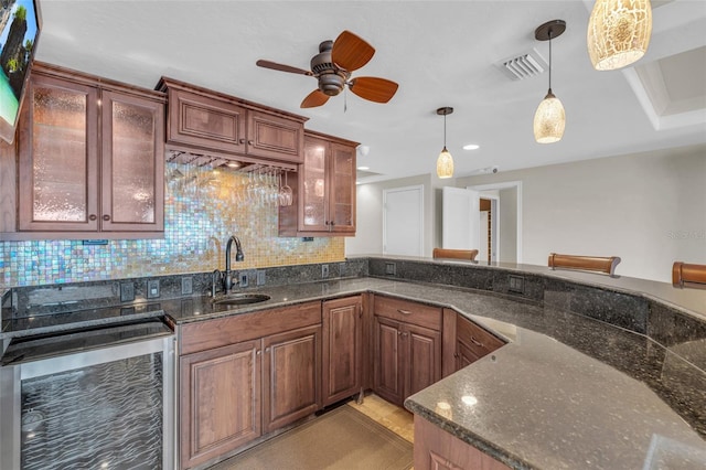 kitchen with dark stone countertops, tasteful backsplash, ceiling fan, decorative light fixtures, and sink