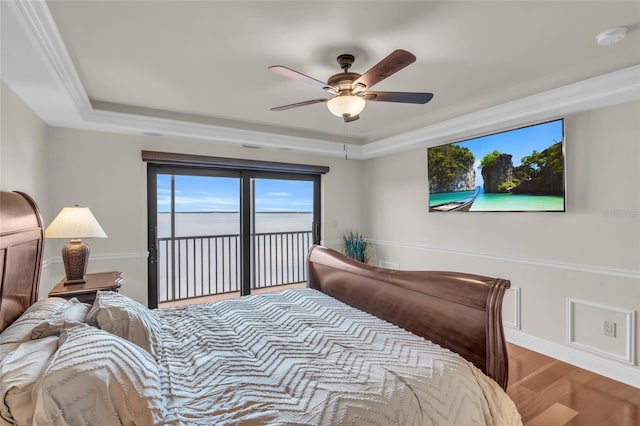 bedroom with access to outside, ceiling fan, a raised ceiling, hardwood / wood-style flooring, and crown molding