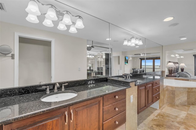 bathroom featuring ceiling fan with notable chandelier, vanity, and a relaxing tiled tub