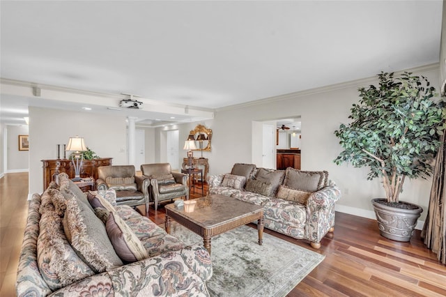 living room with wood-type flooring, decorative columns, ornamental molding, and ceiling fan