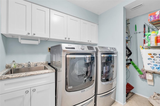 laundry area featuring cabinets, light tile patterned floors, separate washer and dryer, and sink