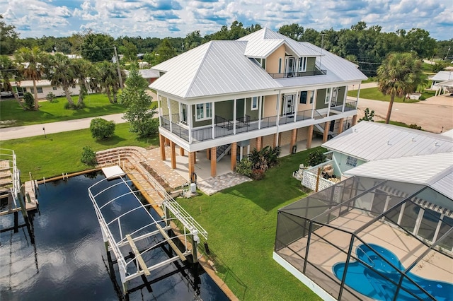 rear view of house with a water view, a yard, a balcony, a patio area, and a lanai