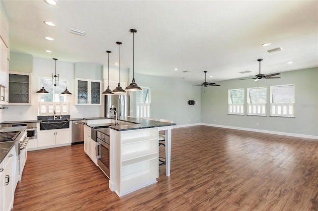 kitchen featuring plenty of natural light, an island with sink, white cabinets, and a breakfast bar